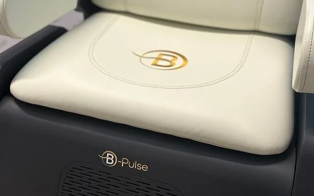 Gros plan sur l'assise en cuir crème de la chaise B-PULSE, avec l'emblème doré B brodé au centre.
