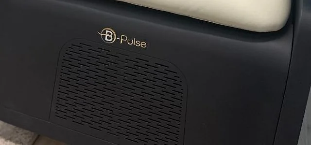 Gros plan sur la base noire de la chaise B-PULSE, avec le logo B-Pulse doré et la grille d'aération.
